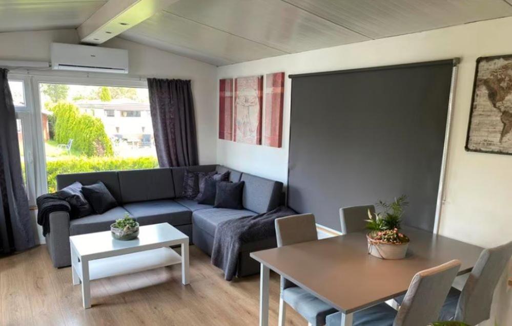 un soggiorno con divano e tavolo di Cozy Chalet in Camping 't Venhop a Berkhout