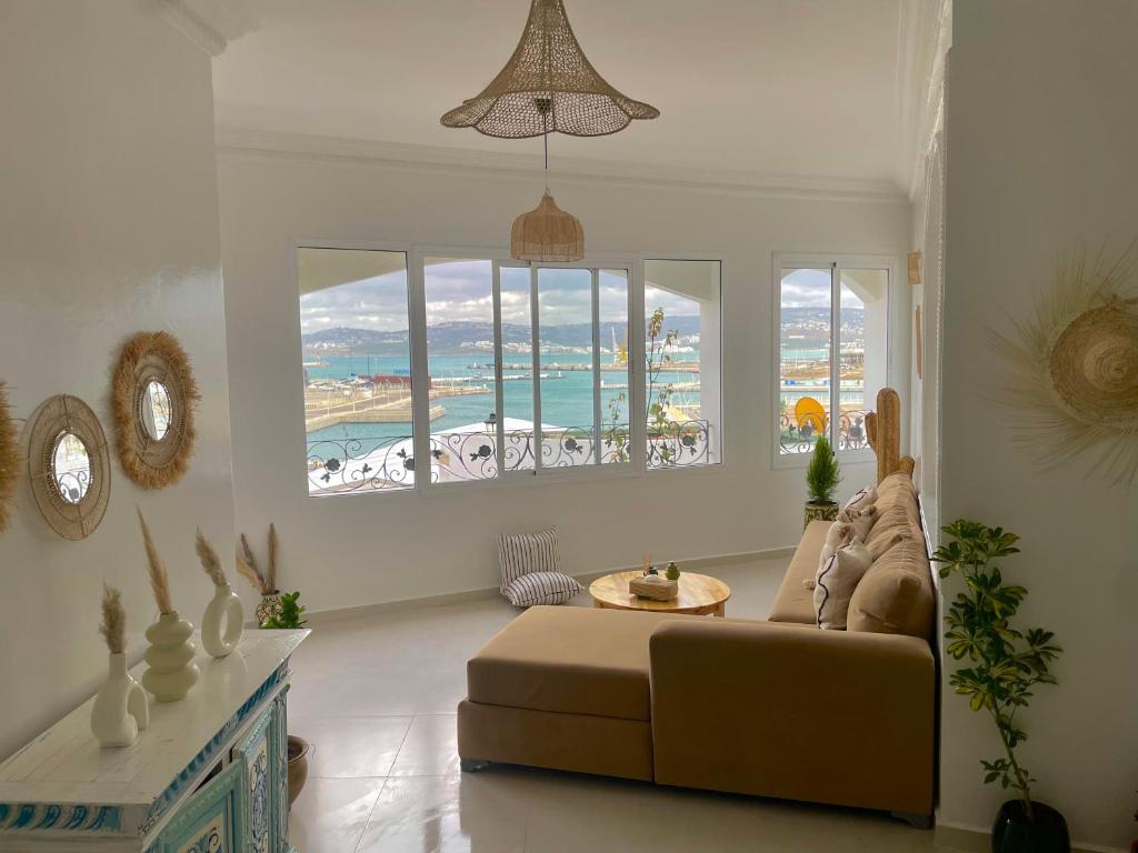 een woonkamer met een bank en uitzicht op de oceaan bij Dar Lahlou in Tanger