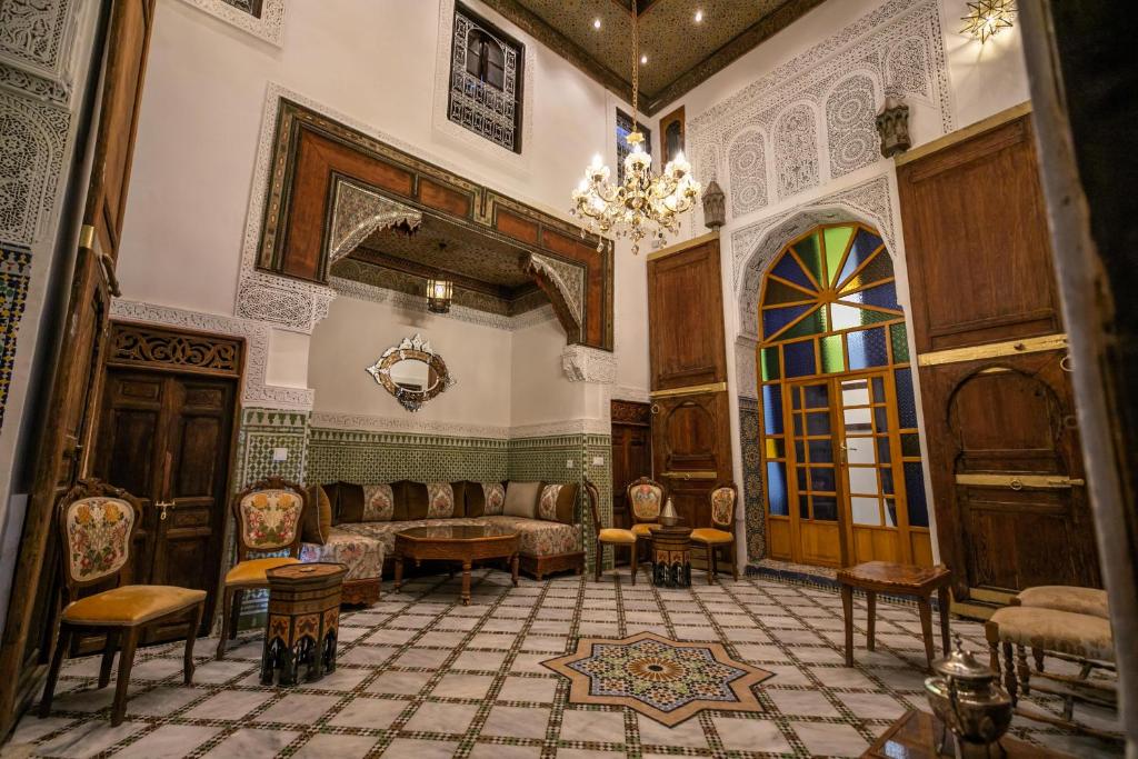 una camera con divano, sedie e lampadario a braccio di Dar Usham Fes a Fes