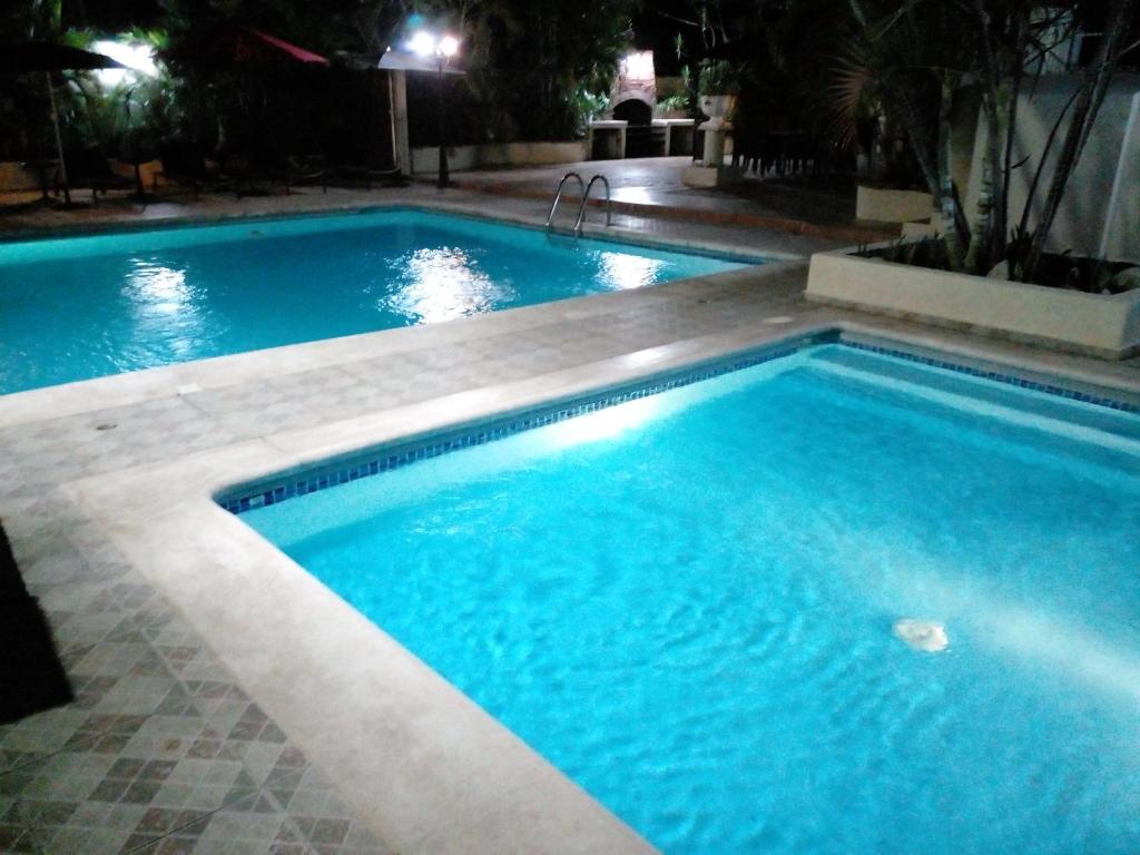 a large swimming pool with blue water at night at Villa Los Almendros - 2 pools and private tennis court in Baní