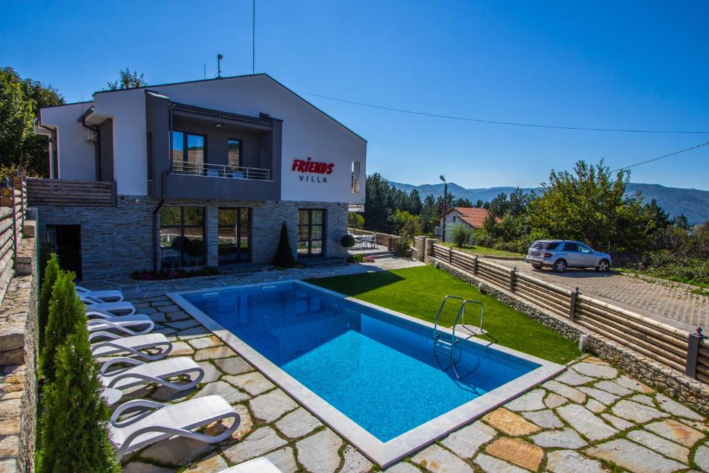 a villa with a swimming pool in front of a house at Family Hotel Friends Villa in Enchets