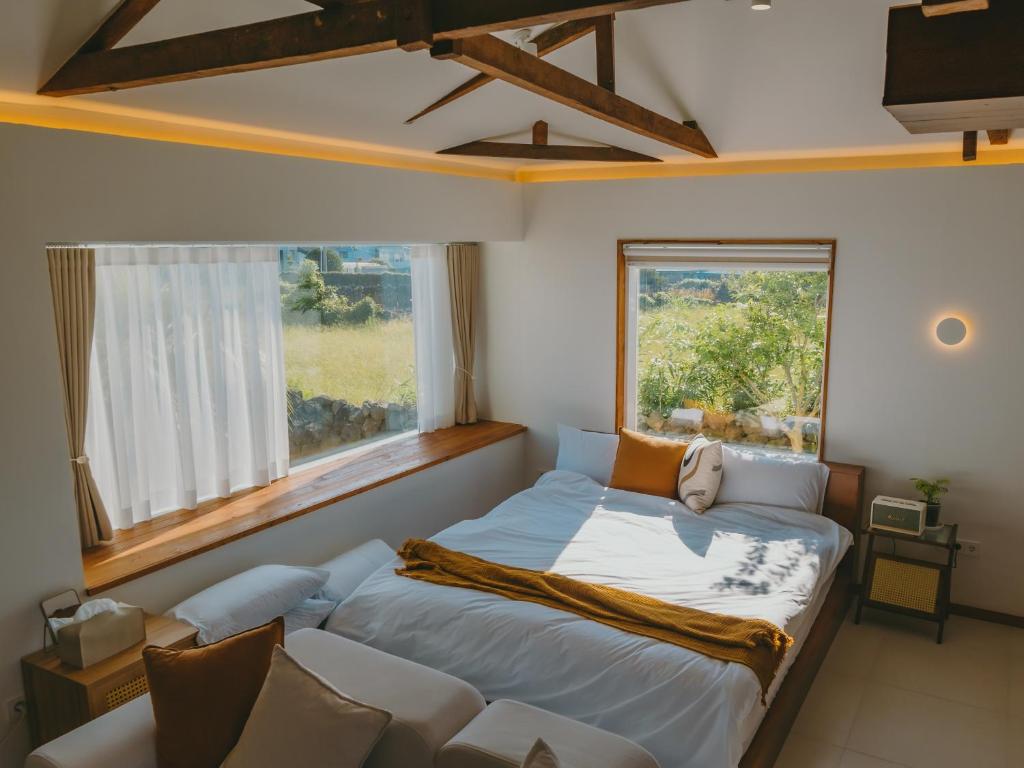 a bedroom with a bed and a couch and a window at 스테이 마음결,애월 자쿠지펜션 in Jeju