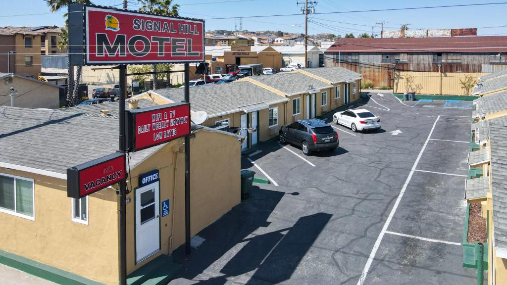 um sinal de motel ao lado de um parque de estacionamento em SIGNAL HILL MOTEL BEACH MOTEL em Long Beach