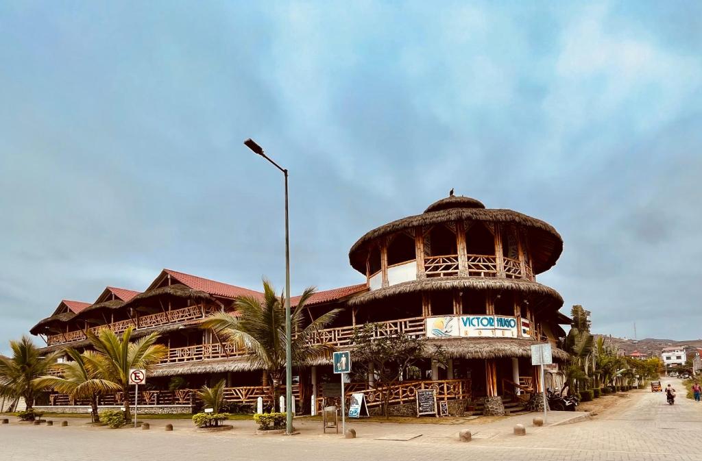 a large building with a clock tower on a street at Victor Hugo Hotel in Puerto López