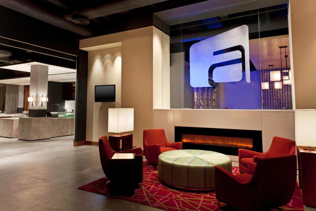 a lobby with red chairs and a fire place at Aloft Nanhai, Foshan in Nanhai