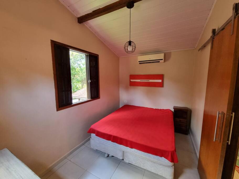 Schlafzimmer mit einem roten Bett und einem Fenster in der Unterkunft Casa praia de camburi in São Sebastião
