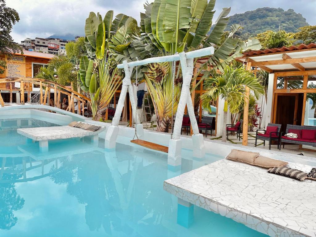 a swimming pool with blue water and plants at Sababa Resort in San Pedro La Laguna