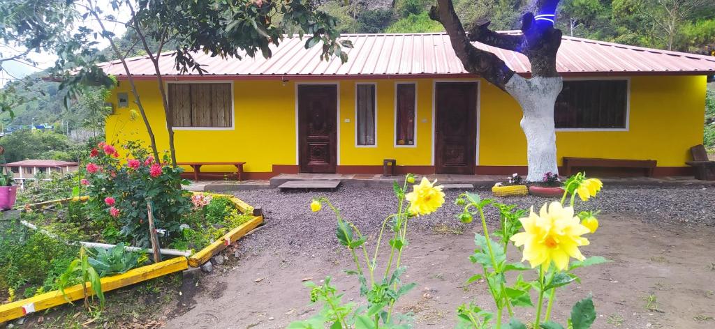 a yellow house with a statue in a garden at Casa Vacacional Los Guayacanes in Baños