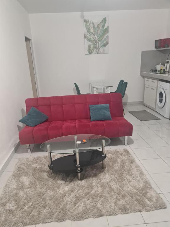 a red couch in a living room with a table at Résidence DENGUELE in Saint-Laurent du Maroni