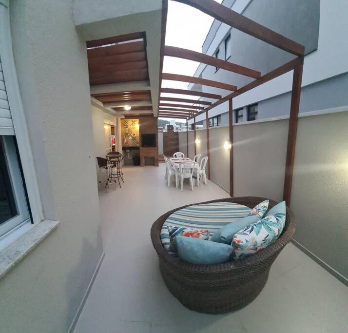 een woonkamer met een rieten bank op een balkon bij Apto Garden em Palmas do Arvoredo in Governador Celso Ramos
