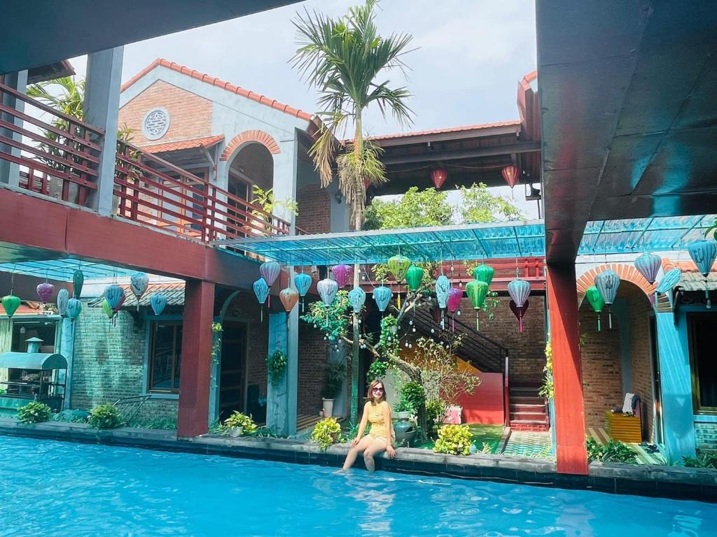 una mujer sentada en el borde de una piscina en Văn Lâm Villa, en Ninh Binh