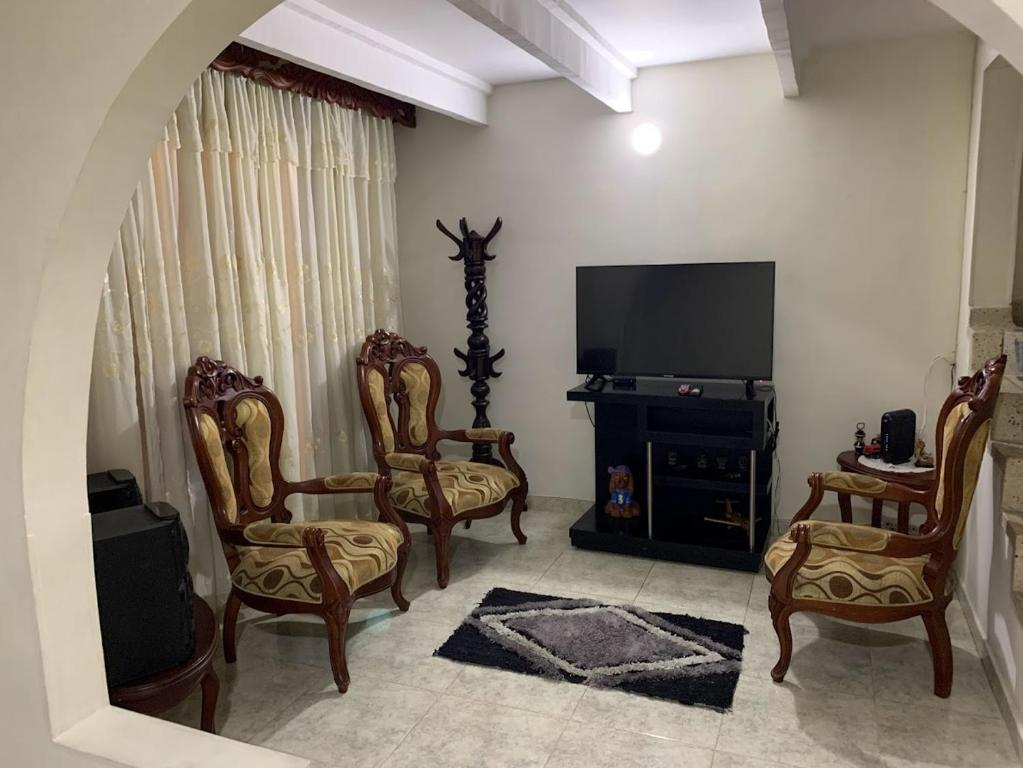 uma sala de estar com cadeiras e uma televisão de ecrã plano em Casa Merce em Pereira