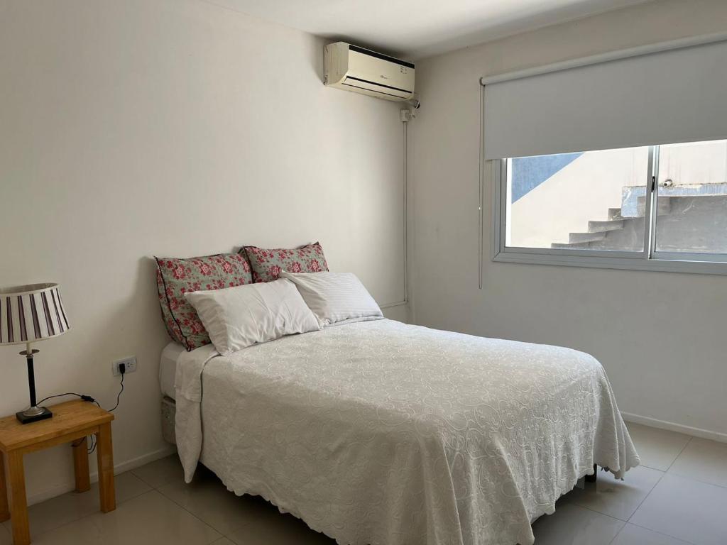 a white bedroom with a bed and a window at Departamento de dos dormitorios y terraza con asador in Yerba Buena