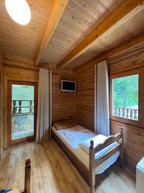 a bed in a wooden room with two windows at Vila Pepaj Razem in Razëm