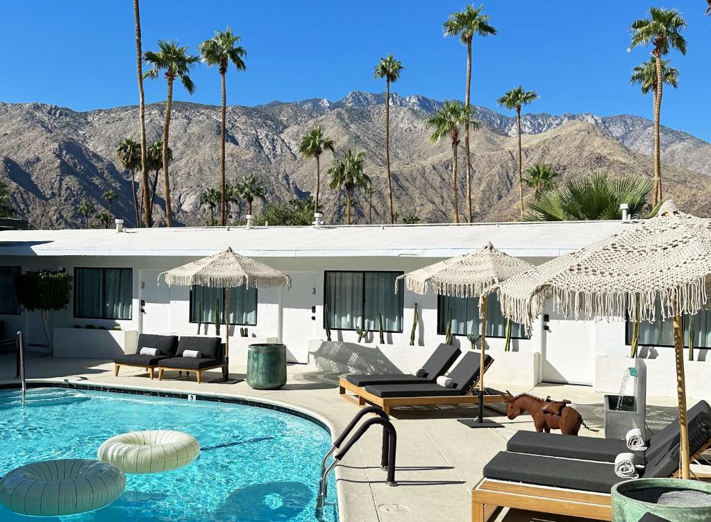 a house with a swimming pool and palm trees at Jazz Hotel Palm Springs in Palm Springs