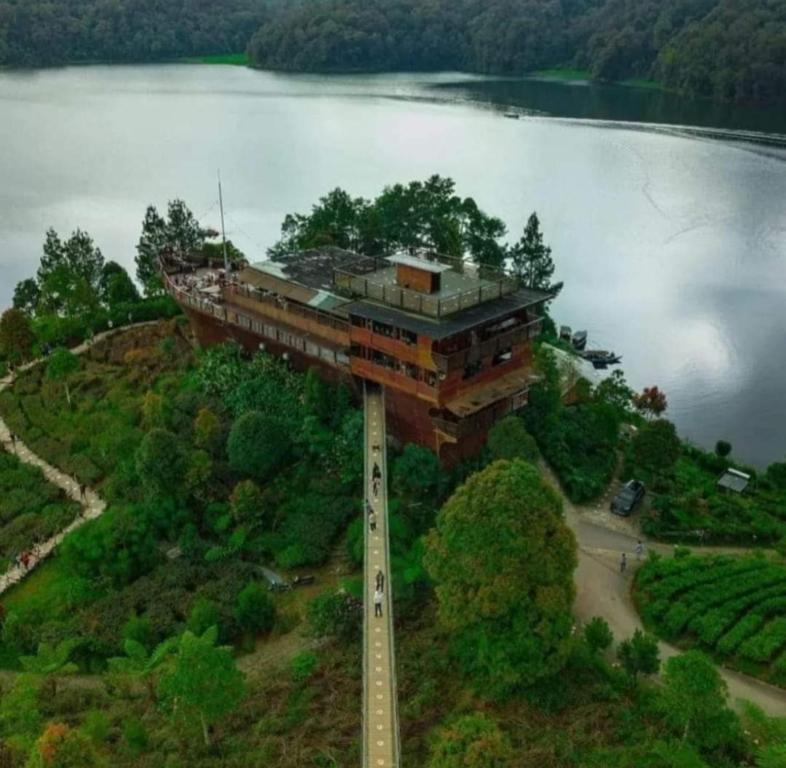 um edifício no topo de uma colina ao lado de um lago em Penginapan sweety homestays em Ciwidey