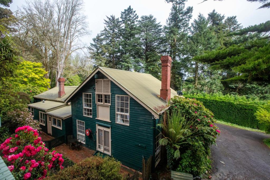 una casa verde con flores en un patio en Ard Choille Cottages, en Mount Macedon