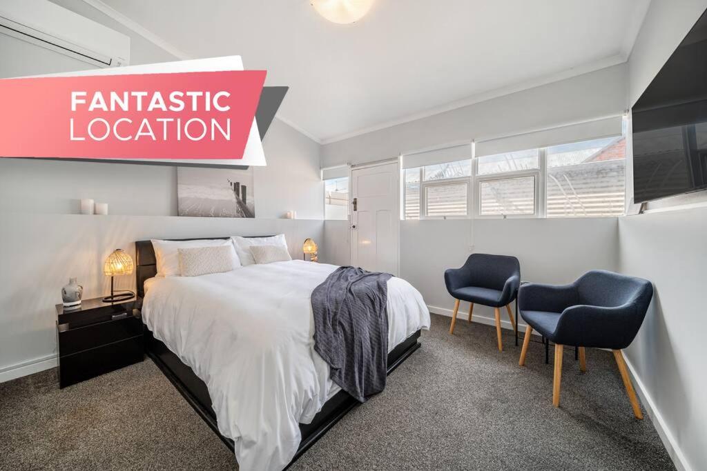 a bedroom with a large bed and two chairs at A Stone's Throw - Cafes, Parking, WiFi in Glenelg