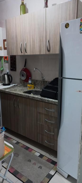 a kitchen with a white refrigerator and wooden cabinets at Apartamento ótima localização in Torres