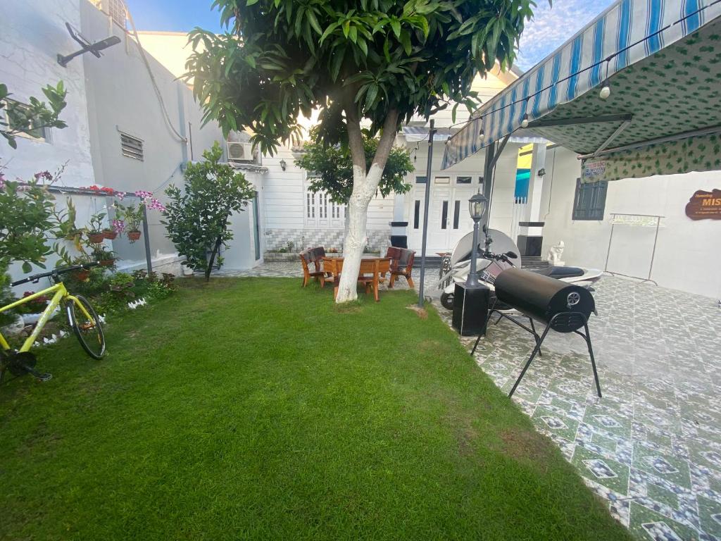a yard with a table and a grill and a tree at Villa sân vườn Misa in Phan Thiet
