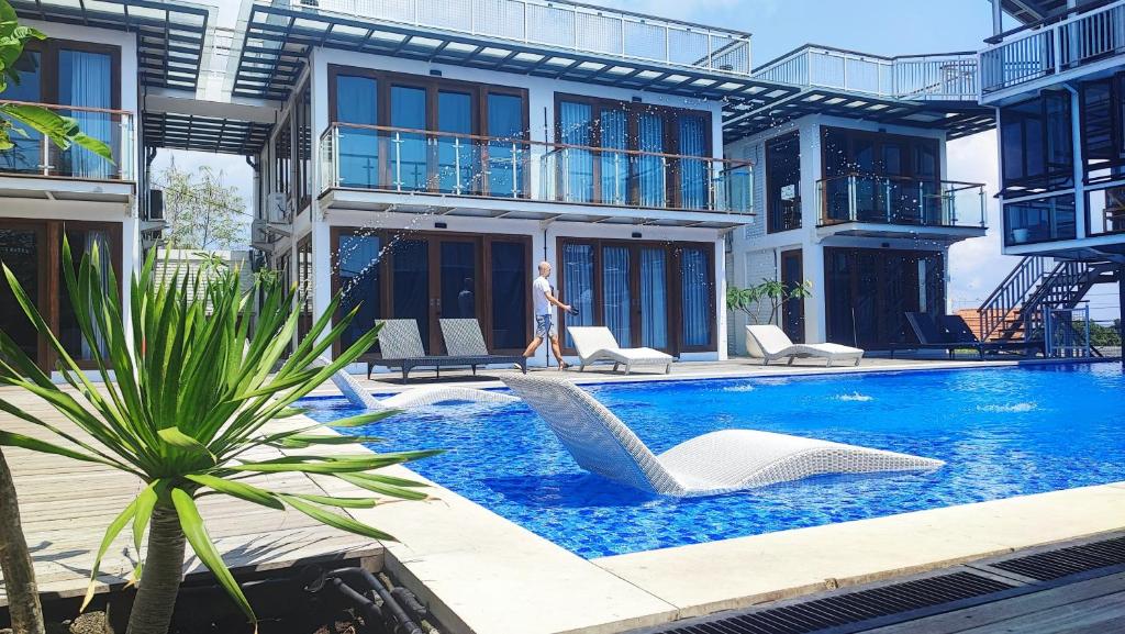 a person walking in front of a building with a swimming pool at SMARANALA in Nusa Dua