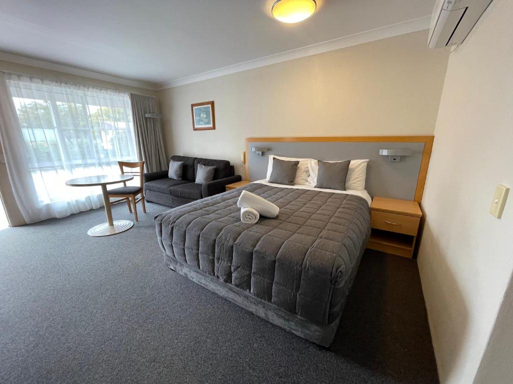 ein Schlafzimmer mit einem Bett, einem Sofa und einem Tisch in der Unterkunft George Bass Motor Inn in Nowra