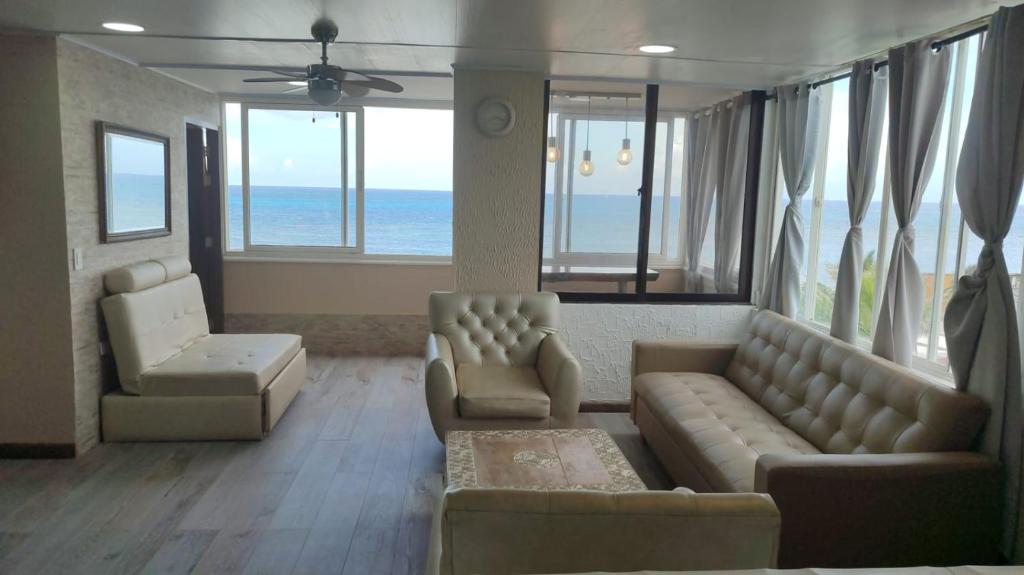 a living room with a couch and chairs and the ocean at Apartamentos Commodore Bay Club in San Andrés