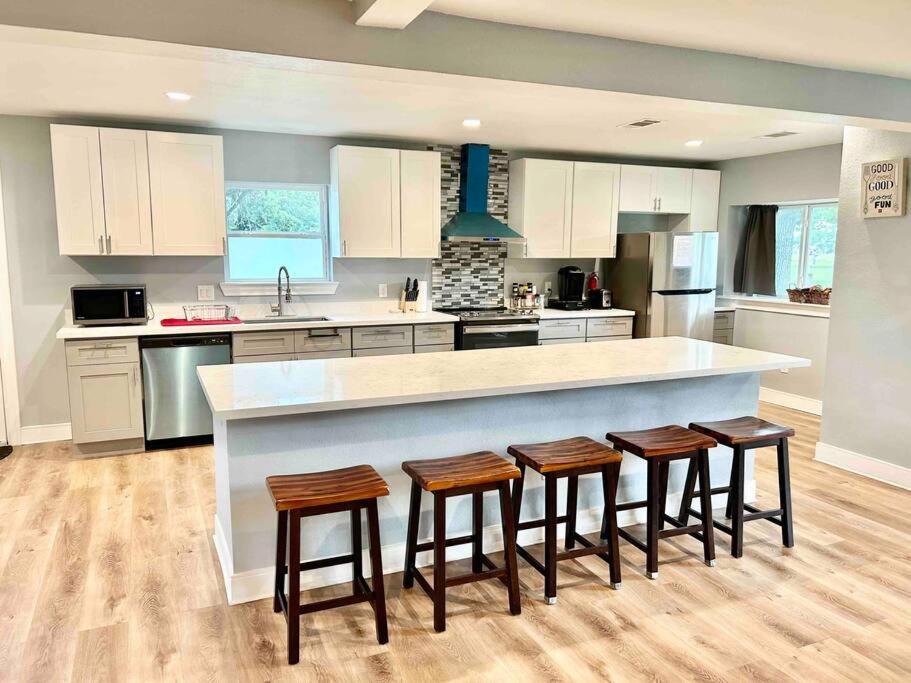 uma cozinha com um grande balcão com quatro bancos de bar em 3300 sq Spacious Kitchen & Living Spaces ( 5 TVs ) em Houston