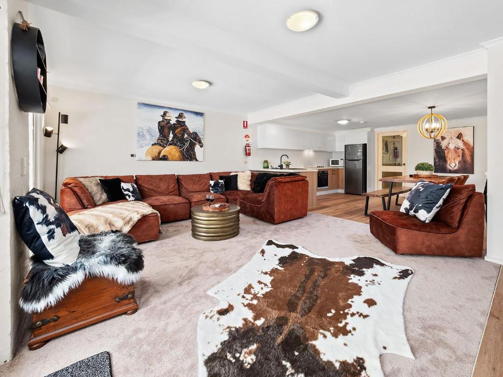 a living room with brown furniture and a kitchen at Inala 7 in Thredbo