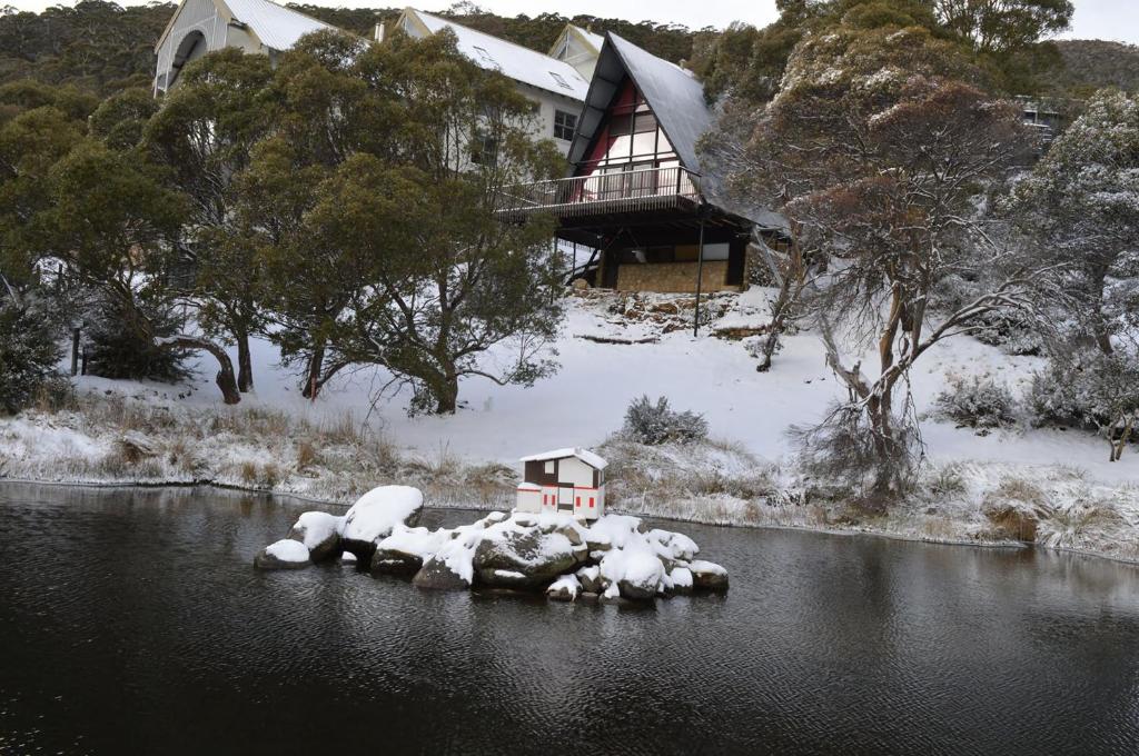 une maison au milieu d'une rivière dans la neige dans l'établissement Moonbah Ski Lodge, à Thredbo