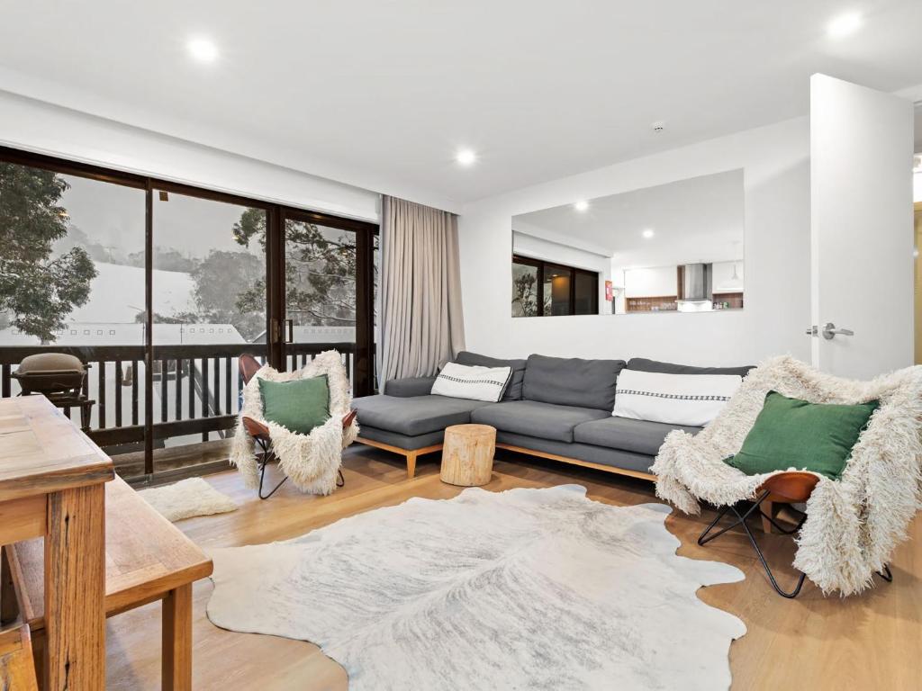 a living room with a couch and chairs and a balcony at Mowamba A1 in Thredbo