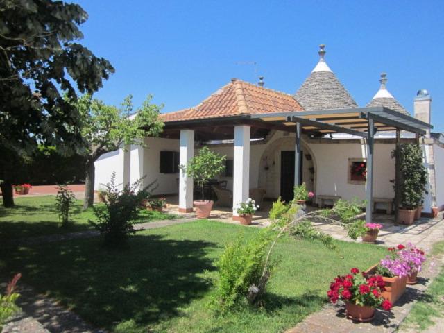 a white house with a gazebo in a yard at Trulli La Ghianda in Noci