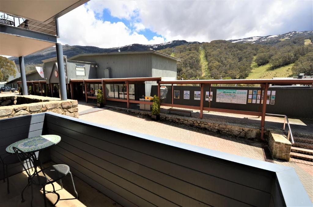 un balcone con tavolo e sgabello e una stazione ferroviaria. di Squatters Run 4 a Thredbo