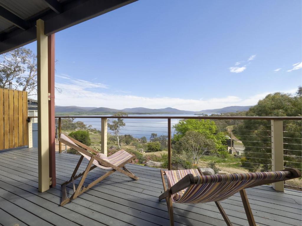 a deck with two chairs and a view of the water at Tulong LakEscape in Jindabyne