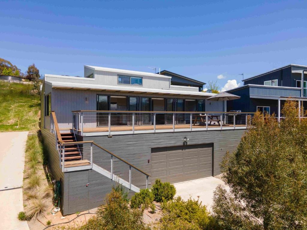 a house with a balcony and a garage at Alpine Freedom in Jindabyne
