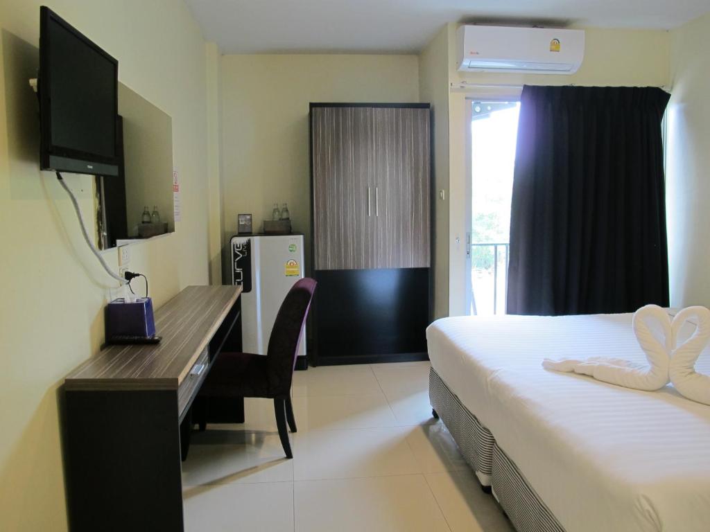 a hotel room with a desk and a bed and a refrigerator at The Airy Residence in Lat Krabang