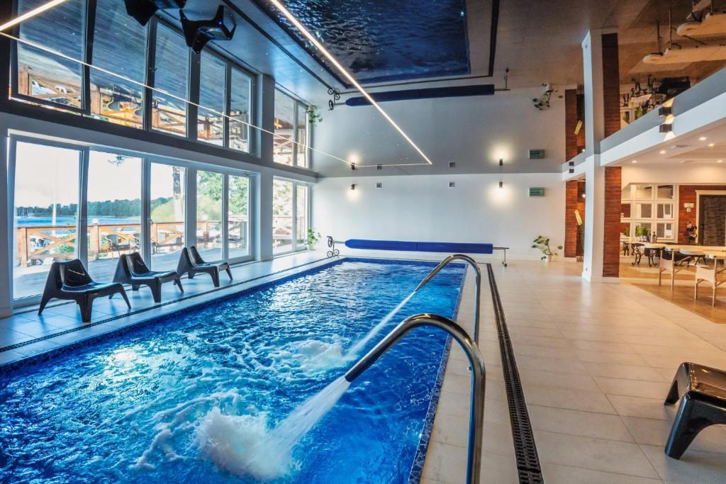 a pool in a building with chairs and a swimming pool at Hotel Tajty in Giżycko