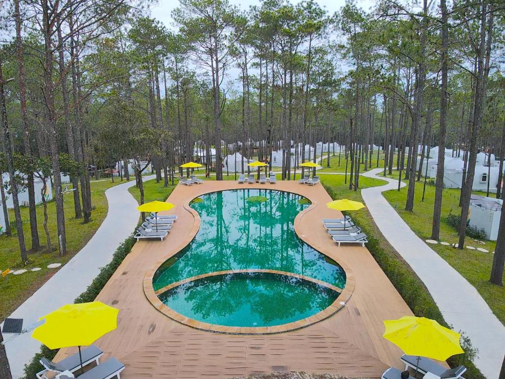 a pool with chairs and umbrellas in a park at Romdoul Kirirom Resort in Kampong Speu