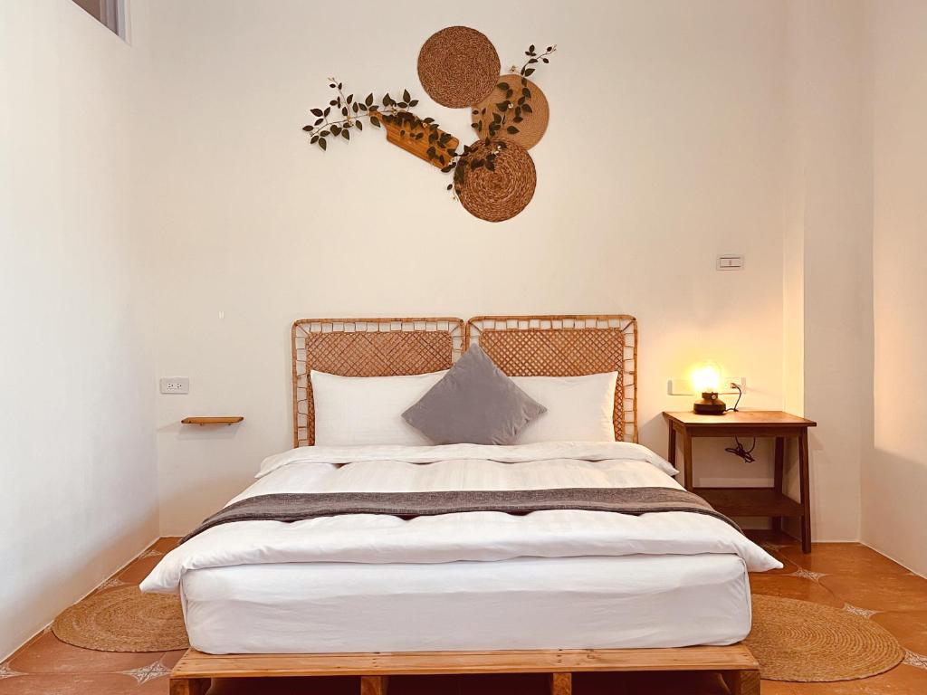 a bedroom with a white bed with a wooden headboard at 亀居Kameshuku in Hengchun South Gate