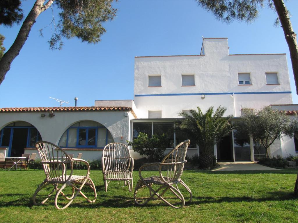 three chairs sitting in the grass in front of a building at Alberg Costa Brava in Llança