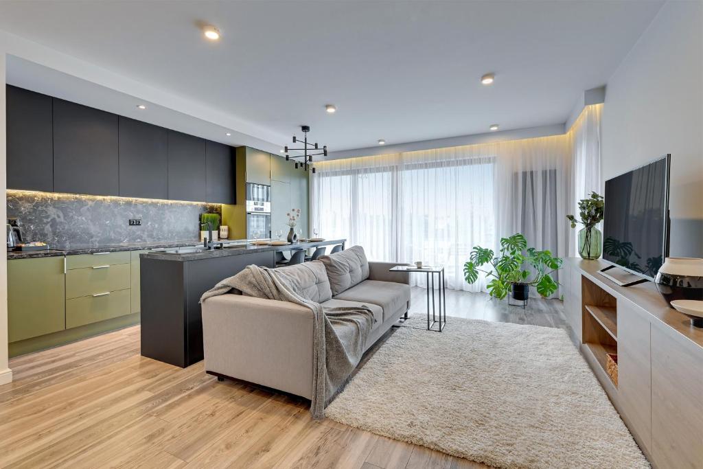 a living room with a couch and a kitchen at Downtown Apartments Riverside Aura Island in Gdańsk