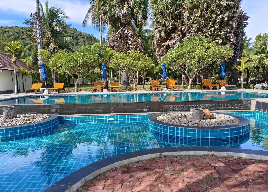 una piscina en un complejo con sillas y árboles en Garto Resort, en Koh Samui 