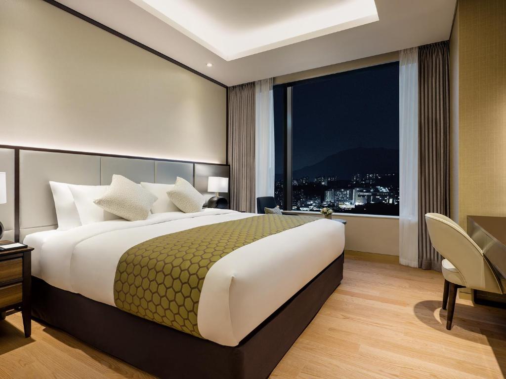 Grand Mercure Ambassador Hotel and Residences Seoul Yongsan في سول: غرفة نوم بسرير كبير ونافذة كبيرة