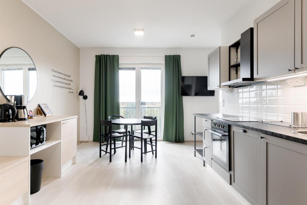 a kitchen with white cabinets and a table and chairs at Serviced Apartments Kuohu Kangasala by UHANDA in Kangasala