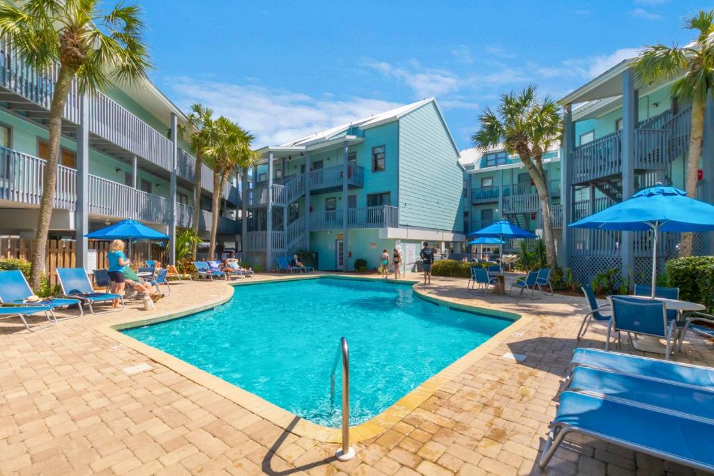a swimming pool with chairs and umbrellas next to a building at Steps to Sand l Ocean views l Smart TVs l Pool in Gulf Shores