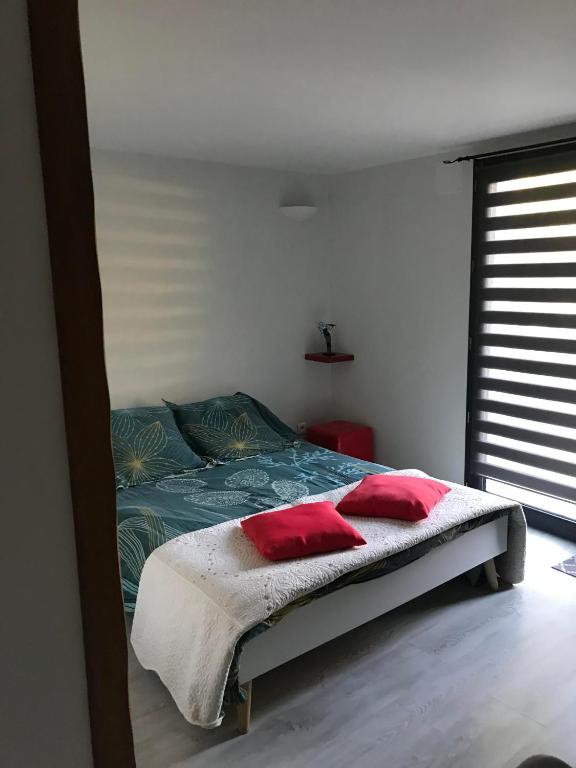 - une chambre avec un lit doté d'oreillers rouges dans l'établissement Chambre indépendante privée avec salle de bain, à La Chapelle-dʼAngillon