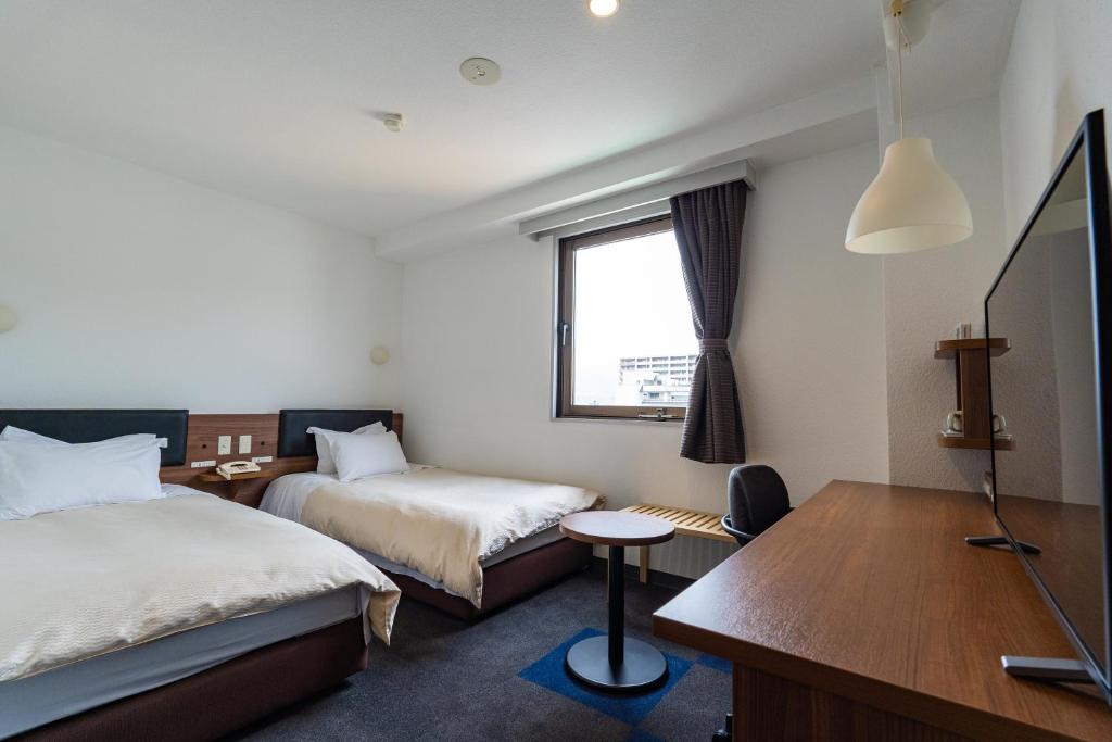 a hotel room with two beds and a desk at Business Hotel Ueno in Yamaguchi
