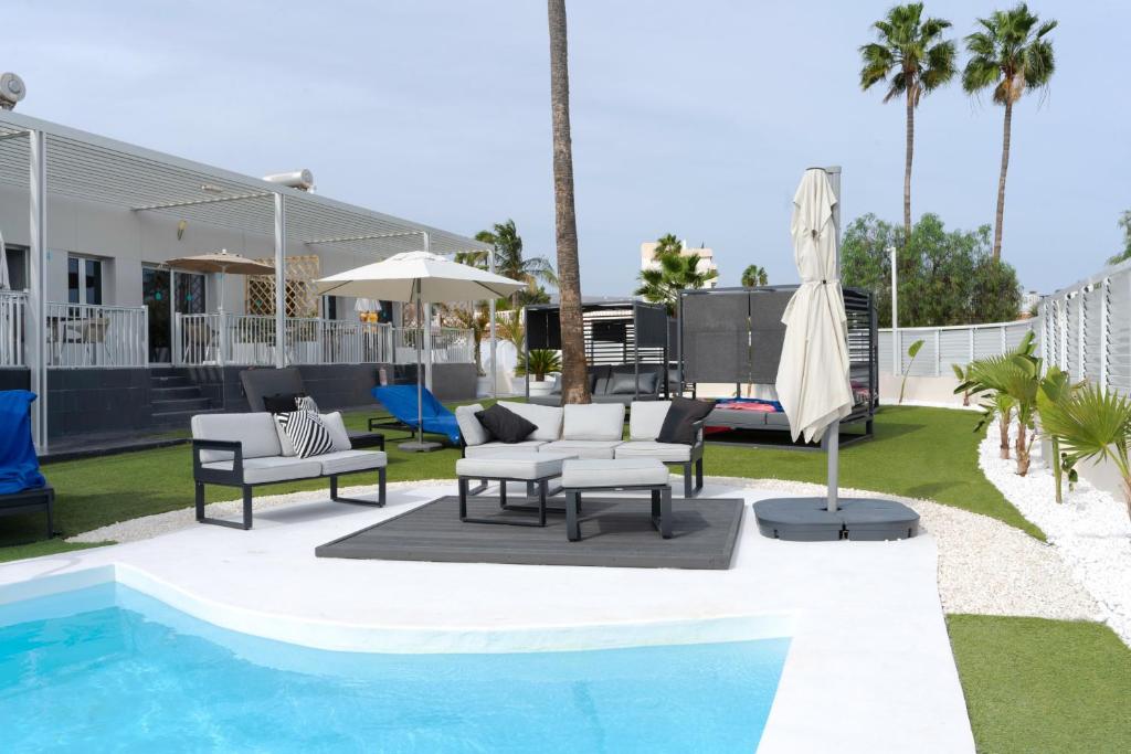 - une piscine avec des chaises et un parasol à côté d'une maison dans l'établissement Tajinaste Beach Gay Men Only, à Playa del Ingles