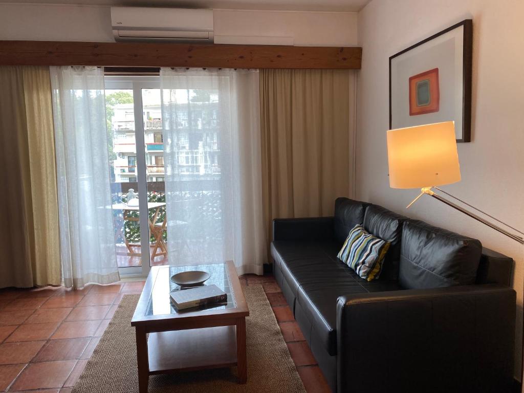 een woonkamer met een zwarte leren bank en een tafel bij Apartment Dom Bosco in Estoril