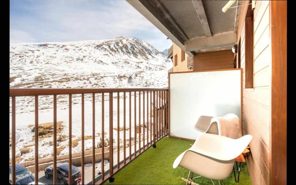 einen Balkon mit einem Stuhl und einem schneebedeckten Berg in der Unterkunft SkiinSkiout Wifi Guardaesquís y Relax TEC in Pas de la Casa
